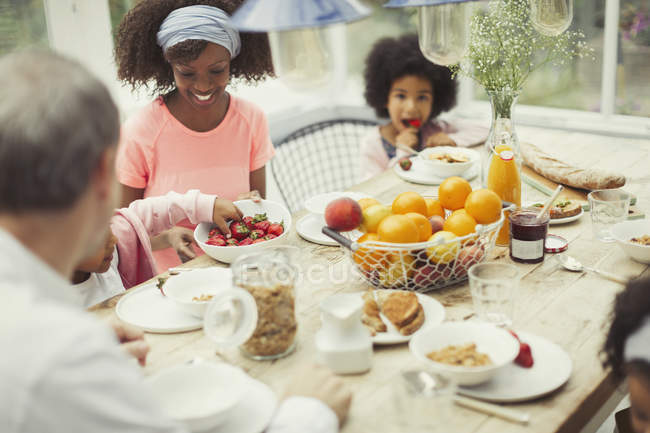 Une jeune famille multi-ethnique prend son petit déjeuner à table — Photo de stock
