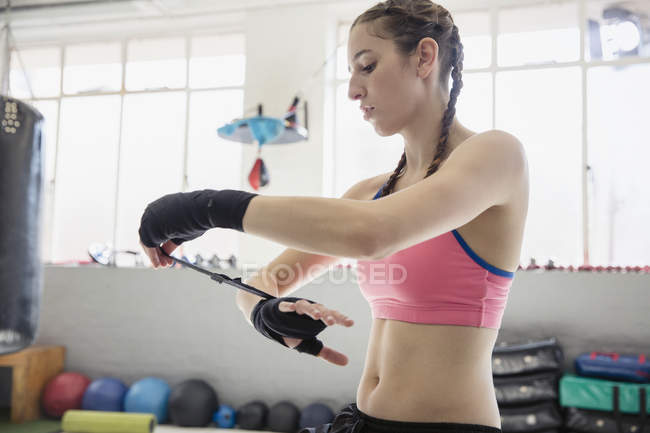 Junge Boxerin wickelt Handgelenke im Fitnessstudio — Stockfoto