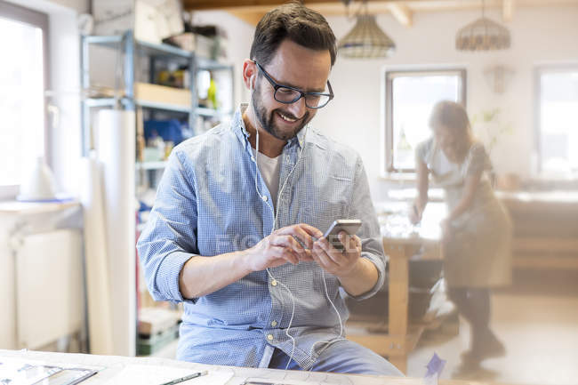 Smiling artist listening to music with earbuds and mp3 player in studio — Stock Photo