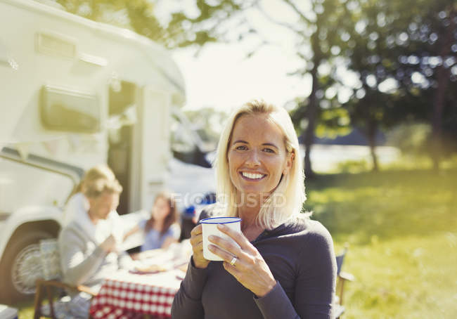 Portrait smiling woman drinking coffee outside sunny motor home — Stock Photo