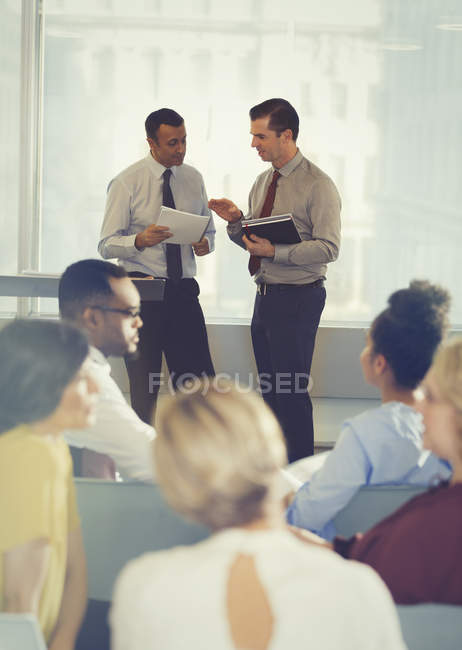 Empresarios hablando en audiencia de conferencia en oficina moderna - foto de stock