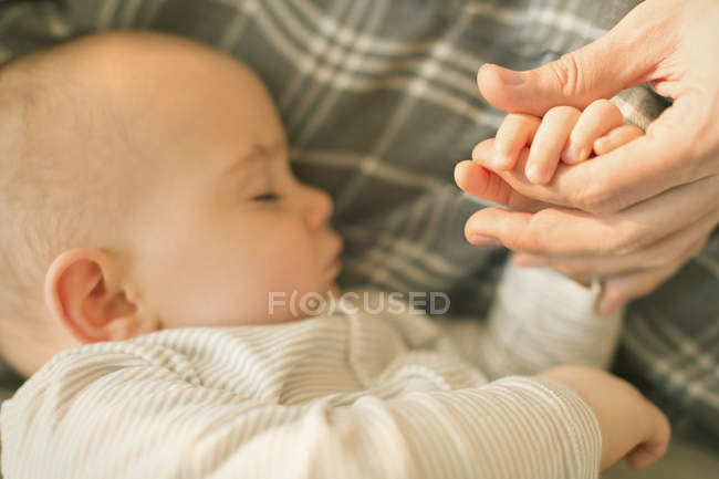Primer plano durmiendo bebé niño cogido de la mano con padre - foto de stock