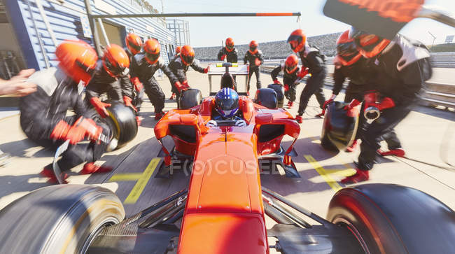 Equipage de stand remplaçant les pneus sur la formule 1 voiture de course dans pit lane — Photo de stock