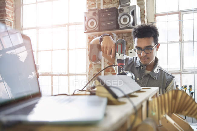 Male designer using power drill in workshop — Stock Photo