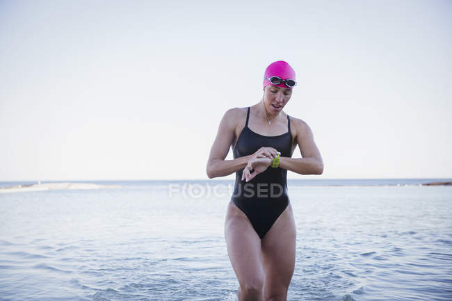 Female active swimmer looking on watch  at ocean outdoors — Stock Photo
