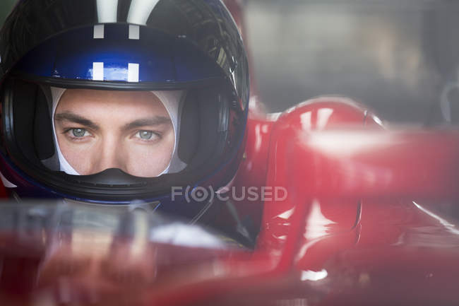 Gros plan formule concentrée un pilote de voiture de course dans le casque regardant loin — Photo de stock