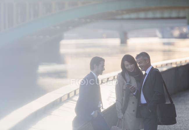 Business people using cell phone at urban waterfront — Stock Photo
