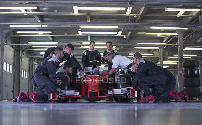 Команда гоночных автомобилей работает над гоночным автомобилем в гараже — стоковое фото