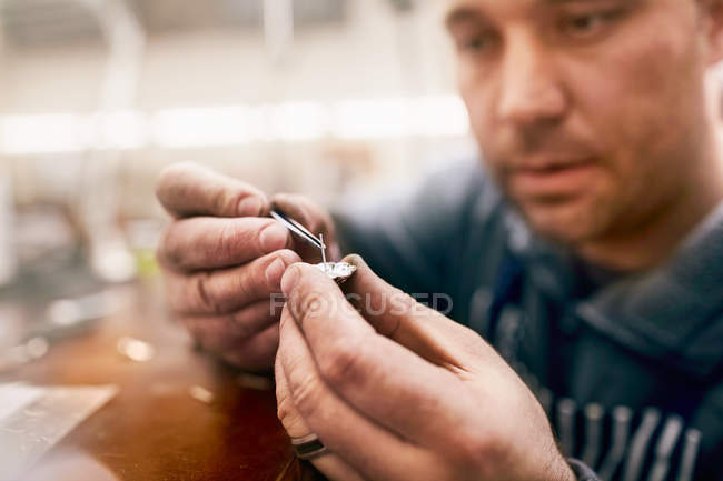 Bijoutier masculin concentré assemblant des bijoux en atelier — Photo de stock