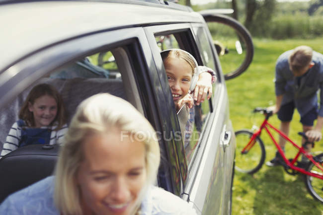 Retrato sonriente chica con familia dentro de coche - foto de stock