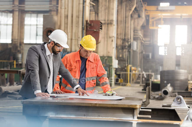 Gerente e engenheiro siderúrgico revisando plantas na fábrica — Fotografia de Stock