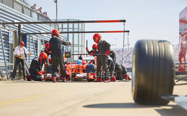 Tripulação de poço trabalhando em um carro de corrida de fórmula um em pit lane — Fotografia de Stock