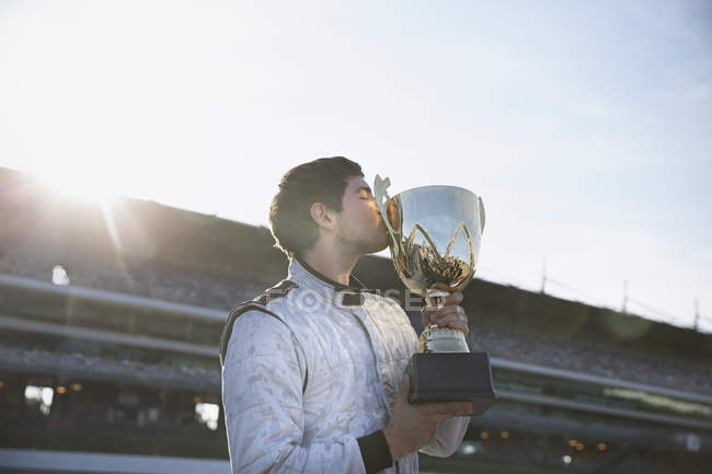 Fórmula masculina um motorista beijando troféu, comemorando a vitória na pista de esportes — Fotografia de Stock