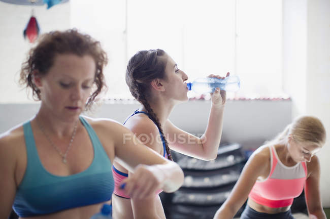 Young women drinking water and resting post workout in gym — Stock Photo