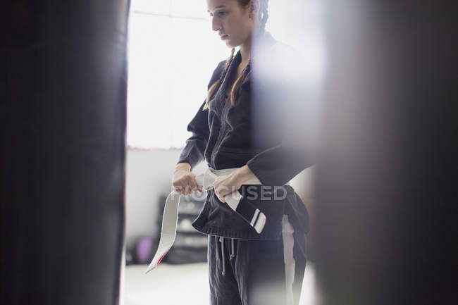 Молодая женщина завязывает пояс дзюдо в спортзале — стоковое фото