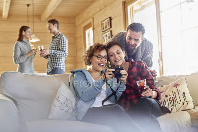 Friends viewing photographs on digital camera on cabin sofa — Stock Photo