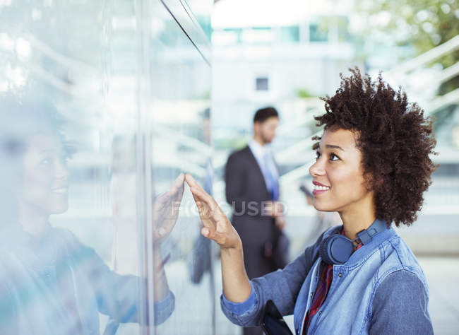 Woman reading transportation schedule at station — Stock Photo