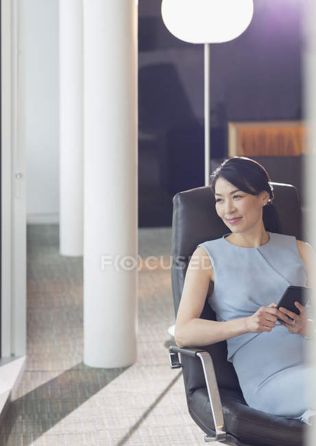 Бизнесвумен, использующая мобильный телефон в офисной гостиной — стоковое фото