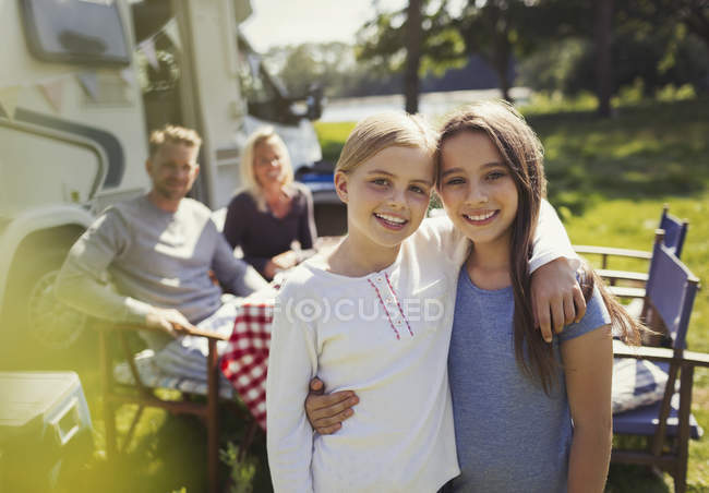 Портрет улыбающихся сестер, обнимающихся возле солнечного дома на колесах — стоковое фото