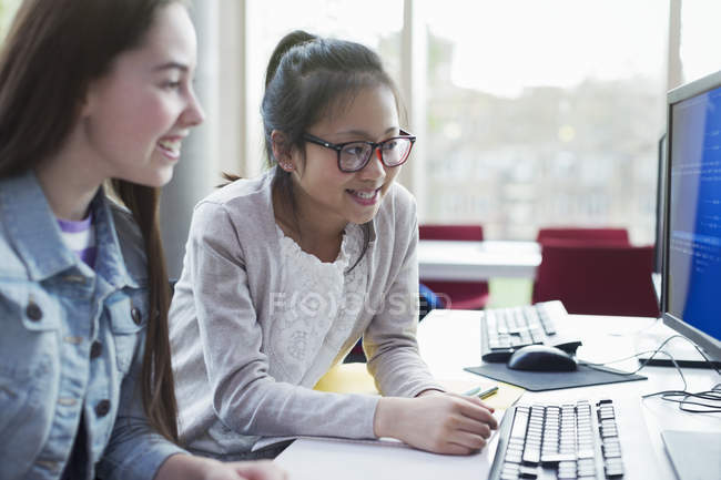 Студенти-дівчата, які навчаються за комп'ютером у бібліотеці — стокове фото