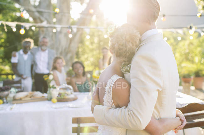 Young couple embracing in garden during wedding reception — Stock Photo