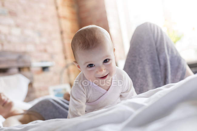 Portrait smiling baby girl laying on bed with mother — Stock Photo