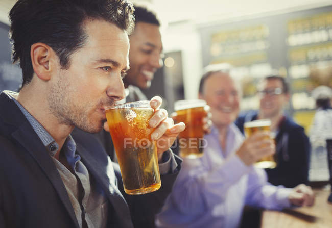 Мужчина пьет пиво с друзьями в баре — стоковое фото
