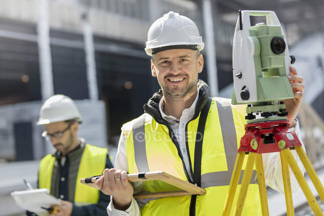 Portrait smiling male engineer using theodolite at construction site — Stock Photo