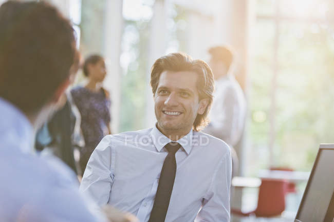 Lächelnder Geschäftsmann hört Amtskollegen zu — Stockfoto
