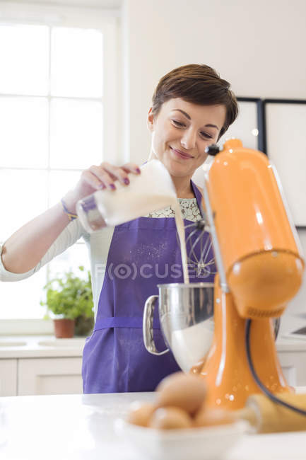 Mulher sorrindo assar, usando stand mixer na cozinha — Fotografia de Stock
