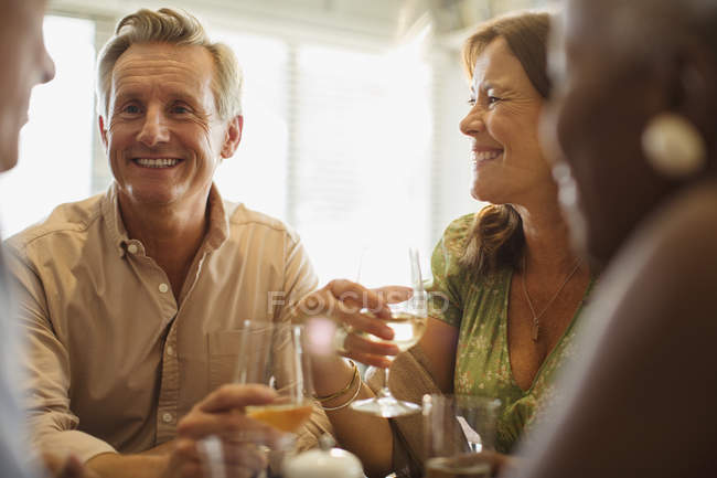 Смеющиеся взрослые пары пьют вино за столом ресторана — стоковое фото