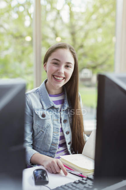 Retrato sonriente, chica confiada estudiante investigando en la computadora en la biblioteca - foto de stock