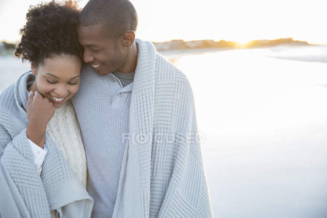 Портрет пары, завернутой в одеяло на пляже — стоковое фото