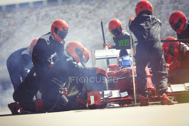 Команда пит-стопа заменяет шины на болиде Формулы-1 в пит-лейн — стоковое фото