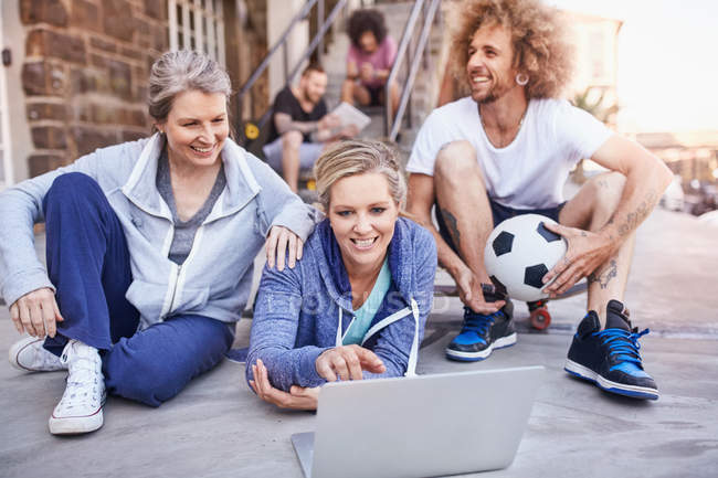 Friends with soccer ball hanging out using laptop — Stock Photo