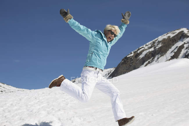 Mulher exuberante brincando na neve — Fotografia de Stock