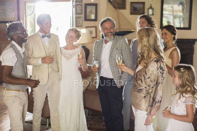 Junges Paar mit Gästen und Sektflöten bei Hochzeitsempfang — Stockfoto
