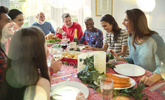 Laughing multi-ethnic family enjoying Christmas dinner at table — Stock Photo