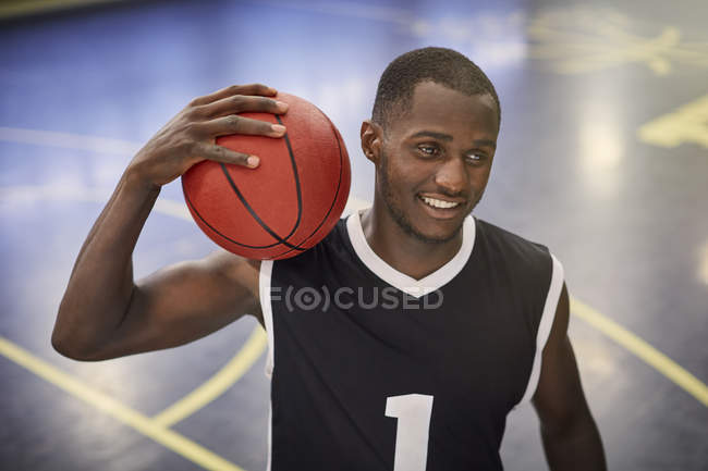 Confiante jovem jogador de basquete masculino segurando basquete na quadra — Fotografia de Stock
