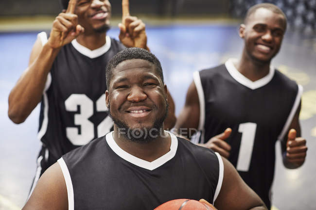 Портрет улыбающийся, уверенный в себе молодой баскетболист команды в черных майках жестом, празднуя победу — стоковое фото