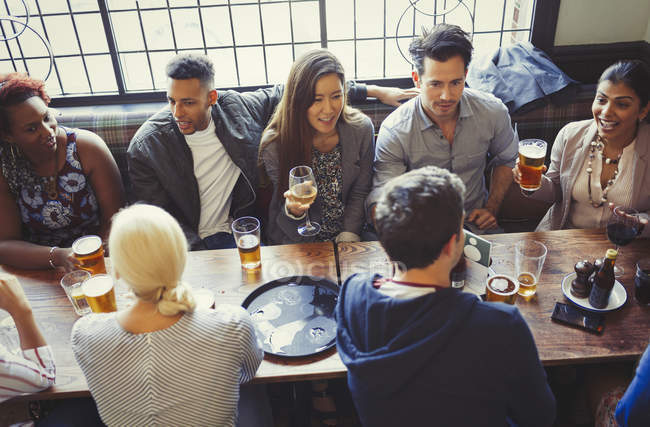 Overhead view of friends drinking beer and wine at table in bar — Stock Photo