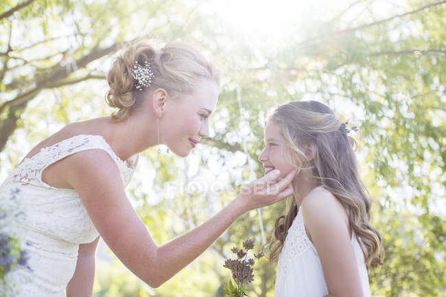 Bride and bridesmaid facing each other in domestic garden during wedding reception — Stock Photo