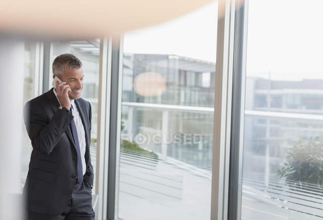 Бізнесмен розмовляє по мобільному телефону у вікні офісу — стокове фото