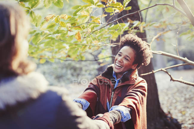 Счастливая женщина, держащаяся за руки с парнем в солнечном осеннем парке — стоковое фото
