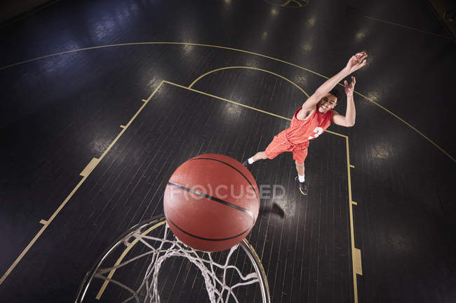 Молодой баскетболист бросает мяч на корте в спортзале — стоковое фото
