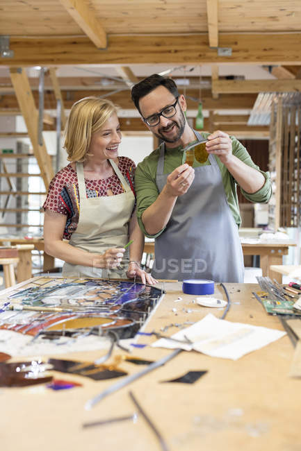 Stained glass artists examining glass pieces in studio — Stock Photo