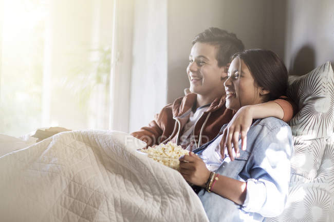 Adolescente coppia sdraiata a letto e guardando la tv — Foto stock