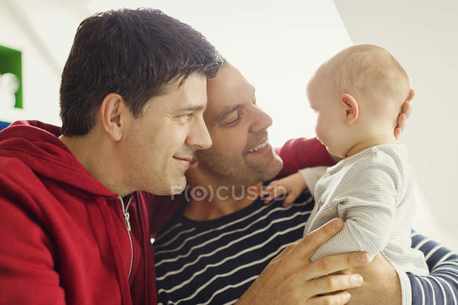 Afectuoso macho gay padres abrazo bebé hijo - foto de stock