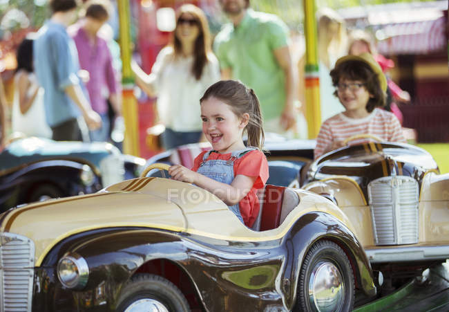 Cheerful girl on carousel in amusement park — Stock Photo
