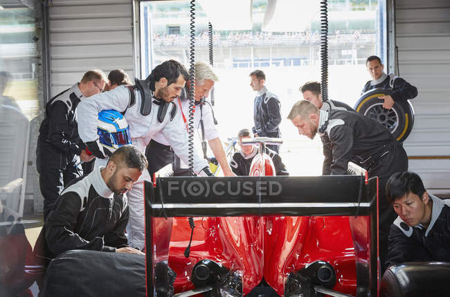 Pit crew preparing formula one race car in repair garage — Stock Photo